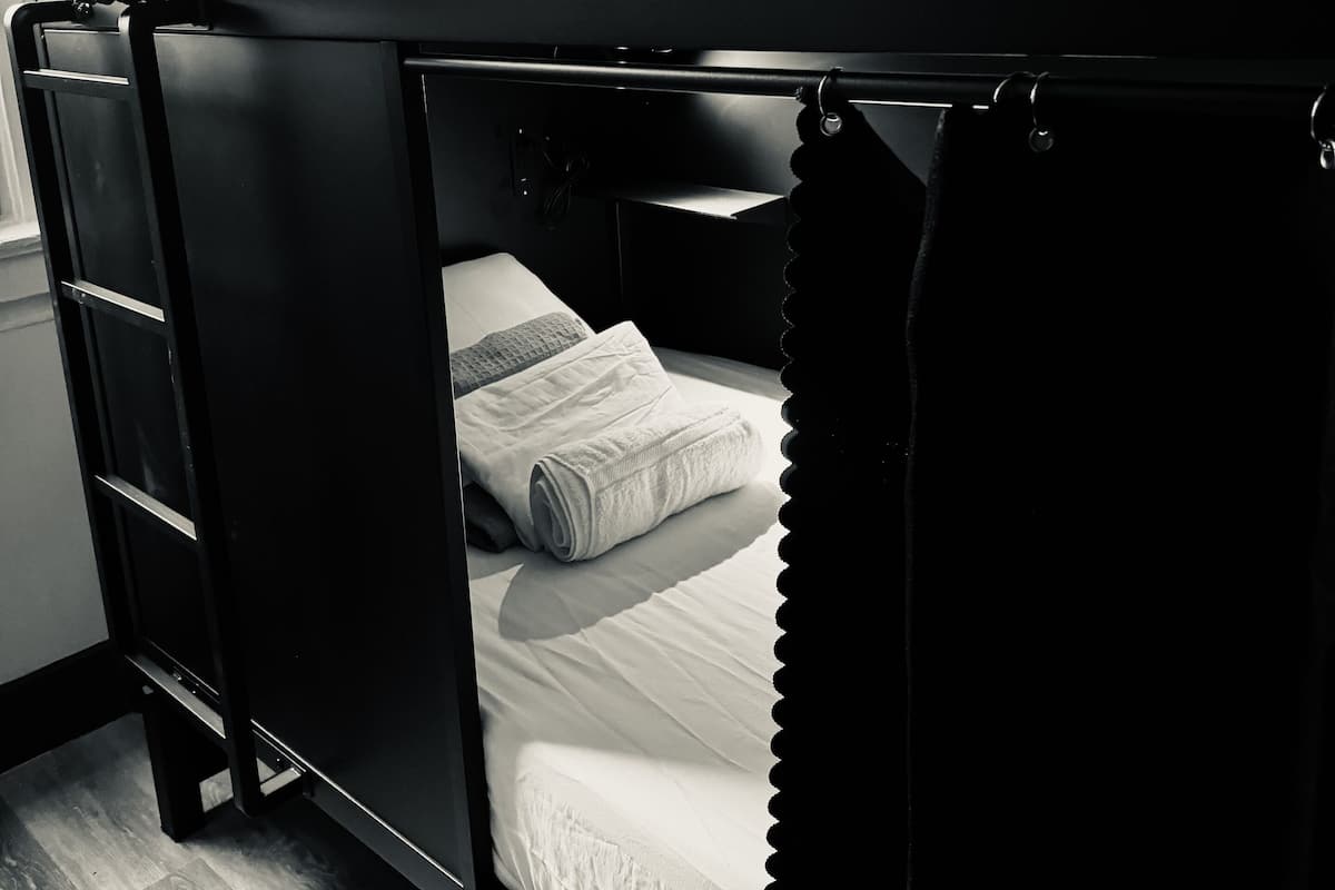 A bunk bed with a lower bed and a top bunk, both with white bedding.