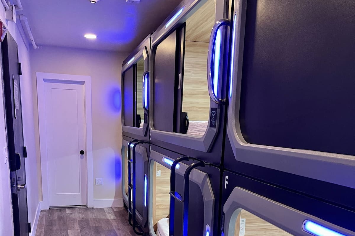 A corridor with bunk beds, wooden flooring, and a white door.