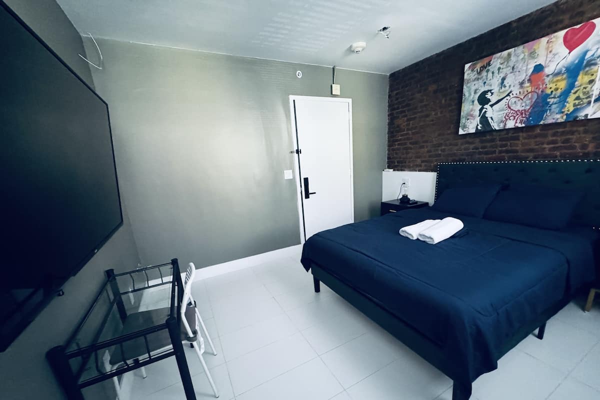 A hotel room with a bed, a TV, a desk, and a chair.
