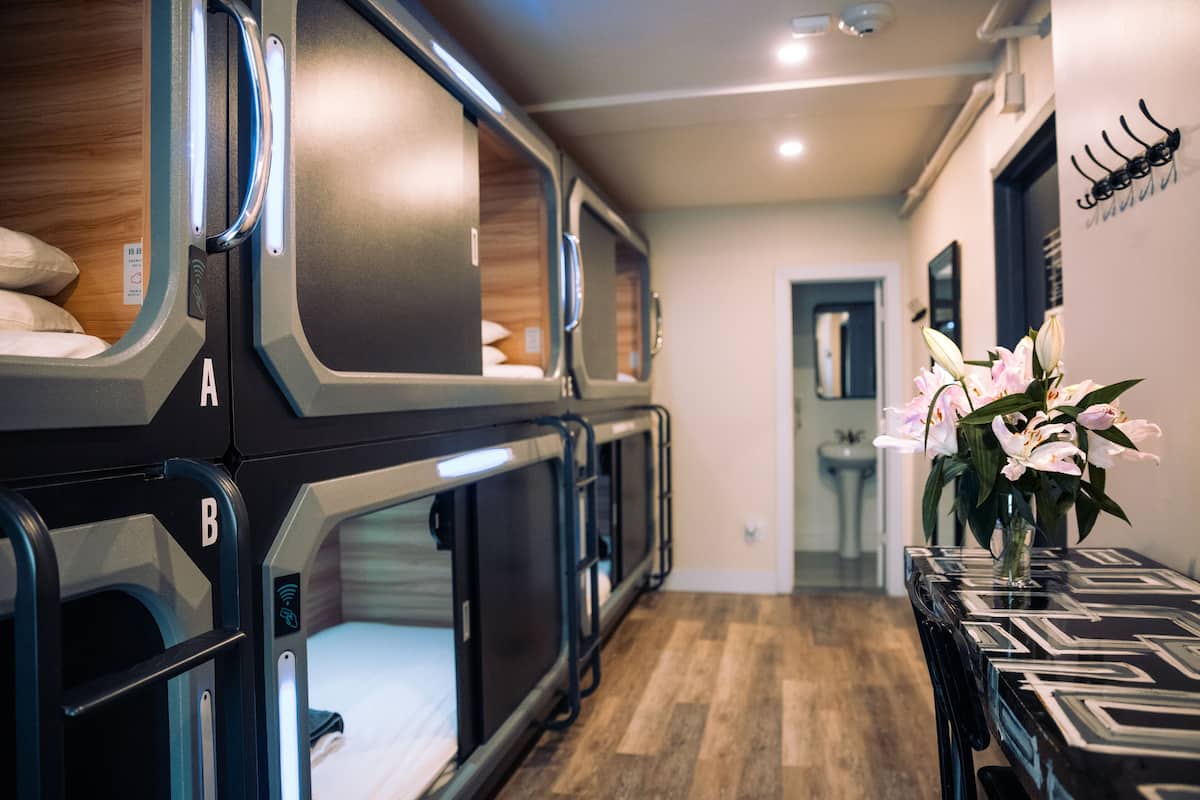 A row of bunk beds with a wooden headboard, a table with a geometric pattern, and a vase with flowers.