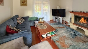 A living room with a sofa, coffee table, TV, fireplace, and a view of the outdoors. - 2 bedroom amazing home in Parzensko (Parzensko)