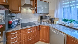 A kitchen with wooden cabinets, a microwave, a sink, and a window with a view. - 2 bedroom amazing home in Parzensko (Parzensko)