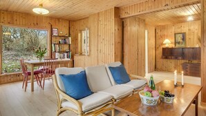 A cozy wooden room with a sofa, a dining table with fruit bowls, and a bookshelf. - 2 bedroom amazing home in Jægerspris (Jægerspris)
