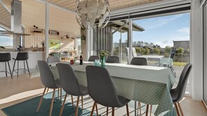 A modern dining area with a large table, chairs, and a view of the outdoors.