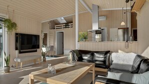 A modern living room with a leather sofa, a coffee table, and a TV mounted on the wall.