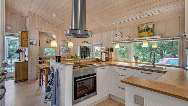 A modern kitchen with wooden cabinets, a central island, stainless steel appliances, and pendant lighting. - Lovely home in Hals with kitchen (Hals)