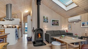 A cozy interior with a fireplace, wooden walls, a dining area, and a kitchen. - Lovely home in Hals with kitchen (Hals)
