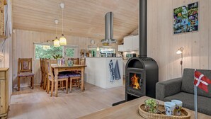 A cozy cabin interior with a dining area, kitchen, and living space featuring a wood stove. - Lovely home in Hals with kitchen (Hals)