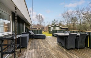 A wooden deck with outdoor furniture, a small building, and a chain-link fence.