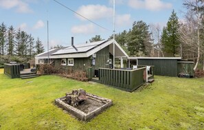 A cabin with a small deck, a fire pit, and a telephone booth.