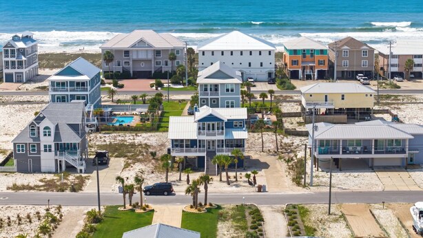 Una zona residenziale sul lungomare, con case e proprietà direttamente sulla spiaggia, tra cui abitazioni con balconi e piscina.