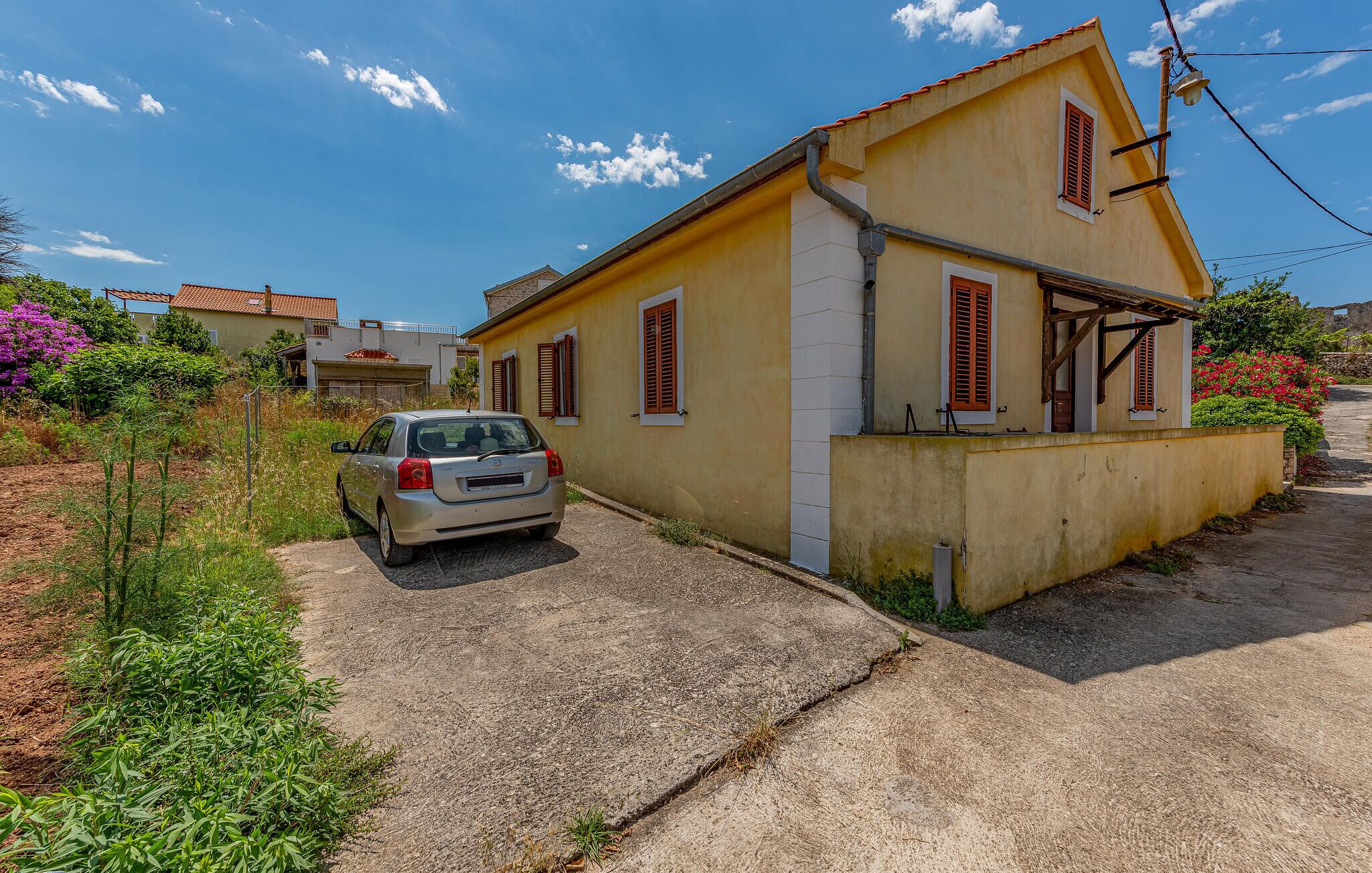 Une maison à deux étages avec une voiture garée devant.