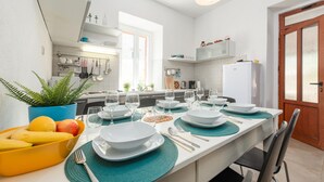 Een moderne keuken met witte kasten, een groot schiereiland met eettafel en een koelkast.