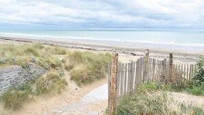 En sandstrand med et træhegn og en stenvæg.