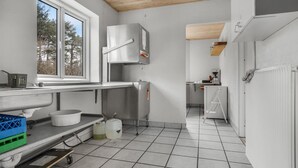A modern kitchen with a large window, stainless steel appliances, and a tiled floor.