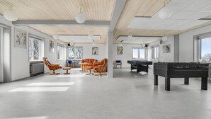 A spacious room with a pool table, foosball table, and leather chairs.