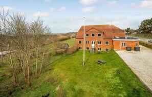 Situated in a rural setting, this charming property features a well-maintained lawn with a bench and flagpole.