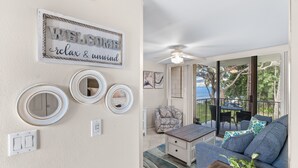 A living room with a sofa, coffee table, and decorative mirrors. There is a ceiling fan and a view of the outdoors through large windows. - Awesome Oceanfront Condo, Great Views, Steps to the Beach, KR#207 (Kihei)