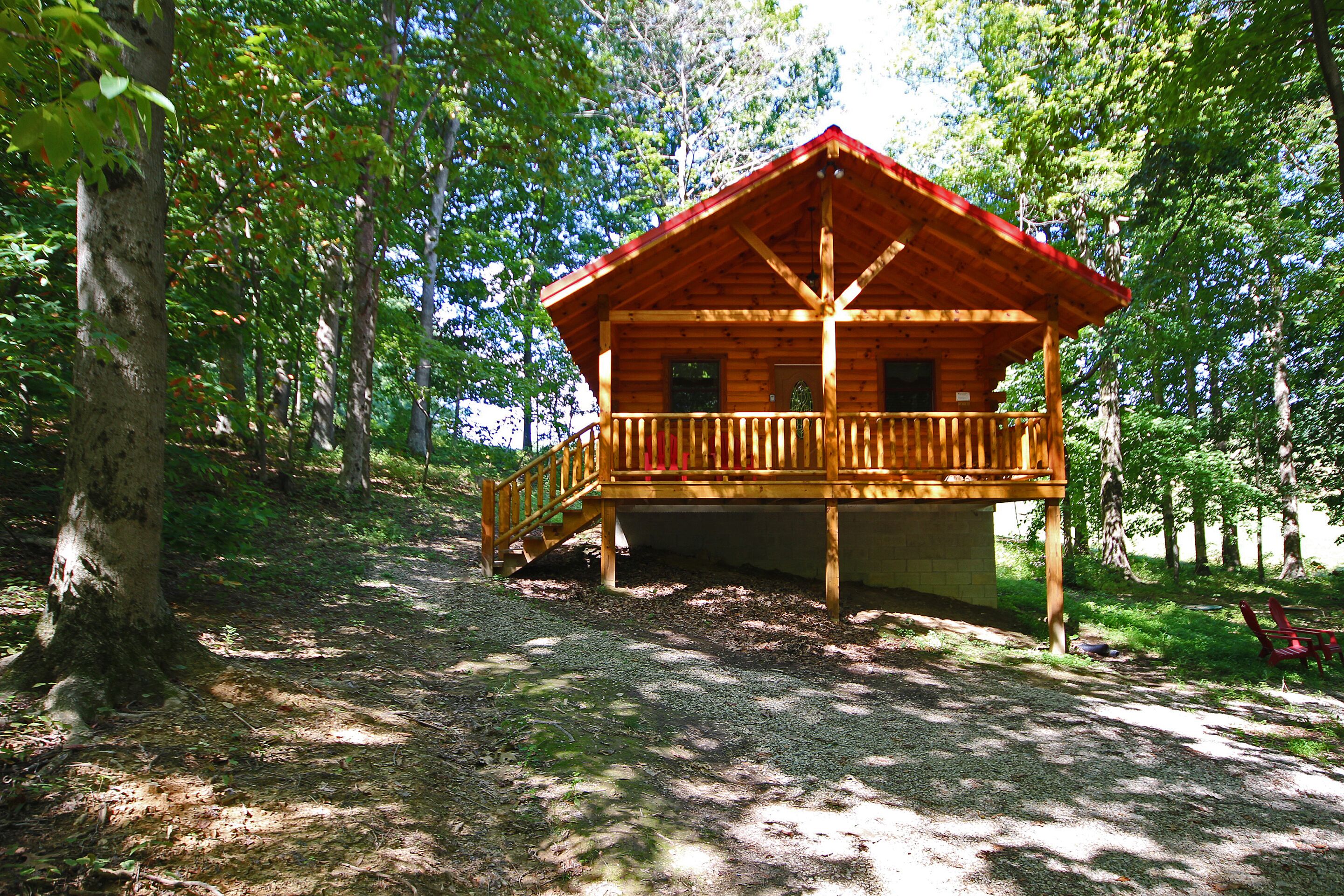 A wooden cabin with a balcony, surrounded by trees.