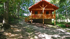 A wooden cabin with a balcony, surrounded by trees.