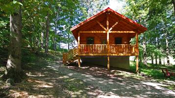 A wooden cabin with a balcony, surrounded by trees.