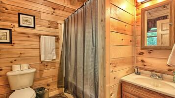 A wooden bathroom with a toilet, sink, and shower curtain.
