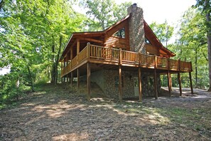 Eine Blockhütte mit einem Steinkamin, einer Holzterrasse und einem Steinfundament.