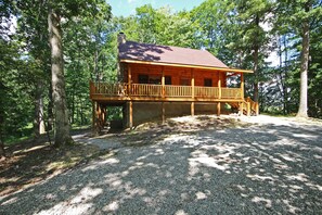 Une cabane en bois dotée d’un balcon, entourée d’arbres.