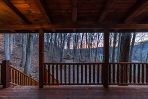 Une terrasse en bois dotée d’une rambarde, qui offre une vue sur une zone boisée.