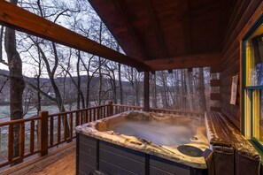 Un jacuzzi en una terraza de madera con vistas a árboles y colinas.