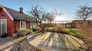 Een rood gebouw met een groene deur, een houten terras en een pad van stenen.
