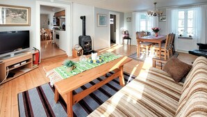 A living room with a TV, wooden furniture, a fireplace, and a dining area with a table set for two.