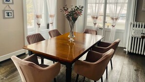 Uma área de refeições com uma mesa de madeira, seis cadeiras e um vaso de flores.