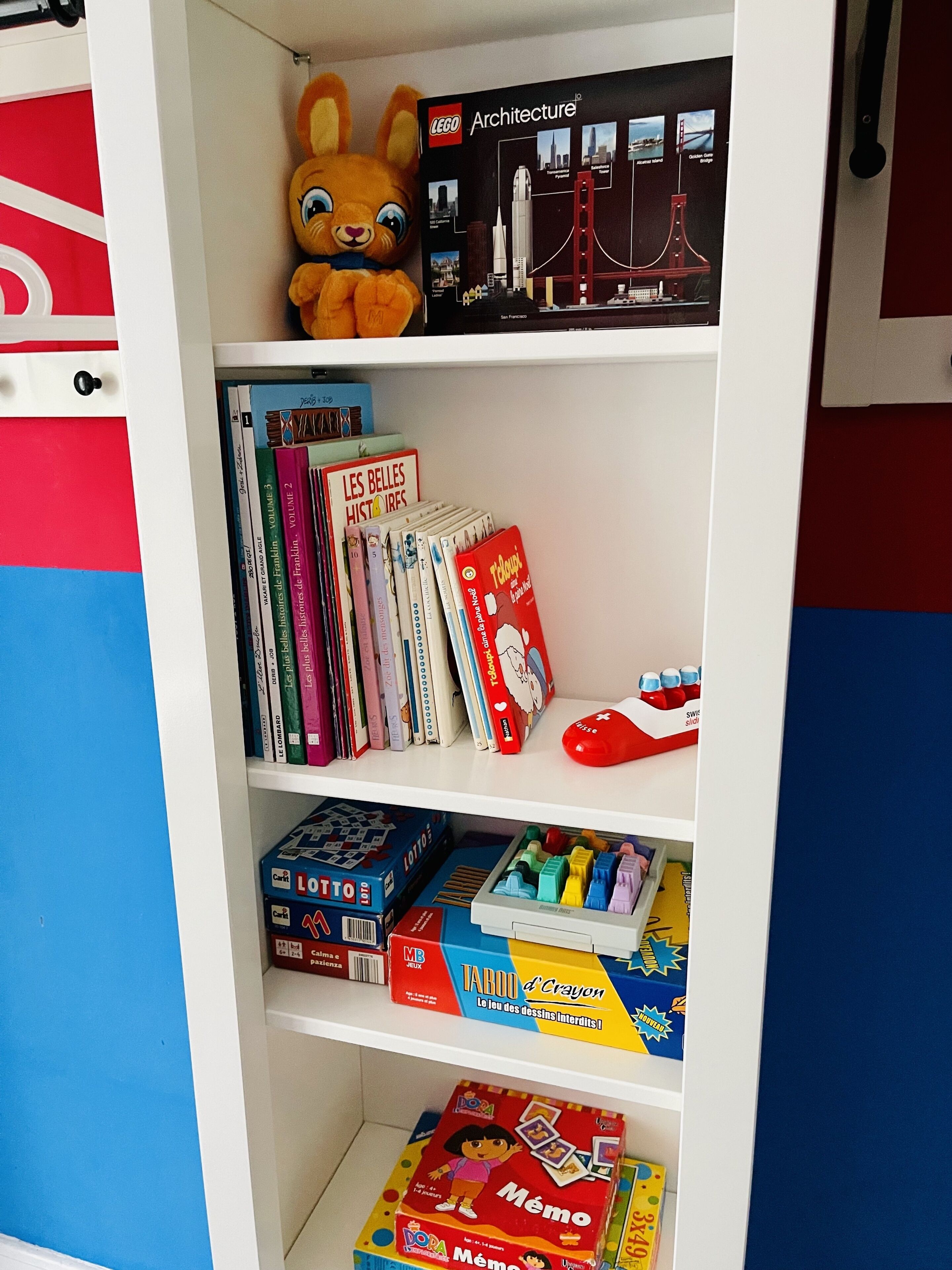 Une bibliothèque remplie de livres, un ensemble de construction LEGO Architecture et un jouet en peluche.