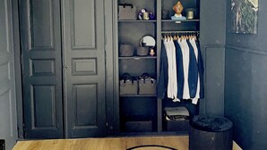 Quarto com um guarda-roupa grande, luminária pendente e cama com cobertura estampada.