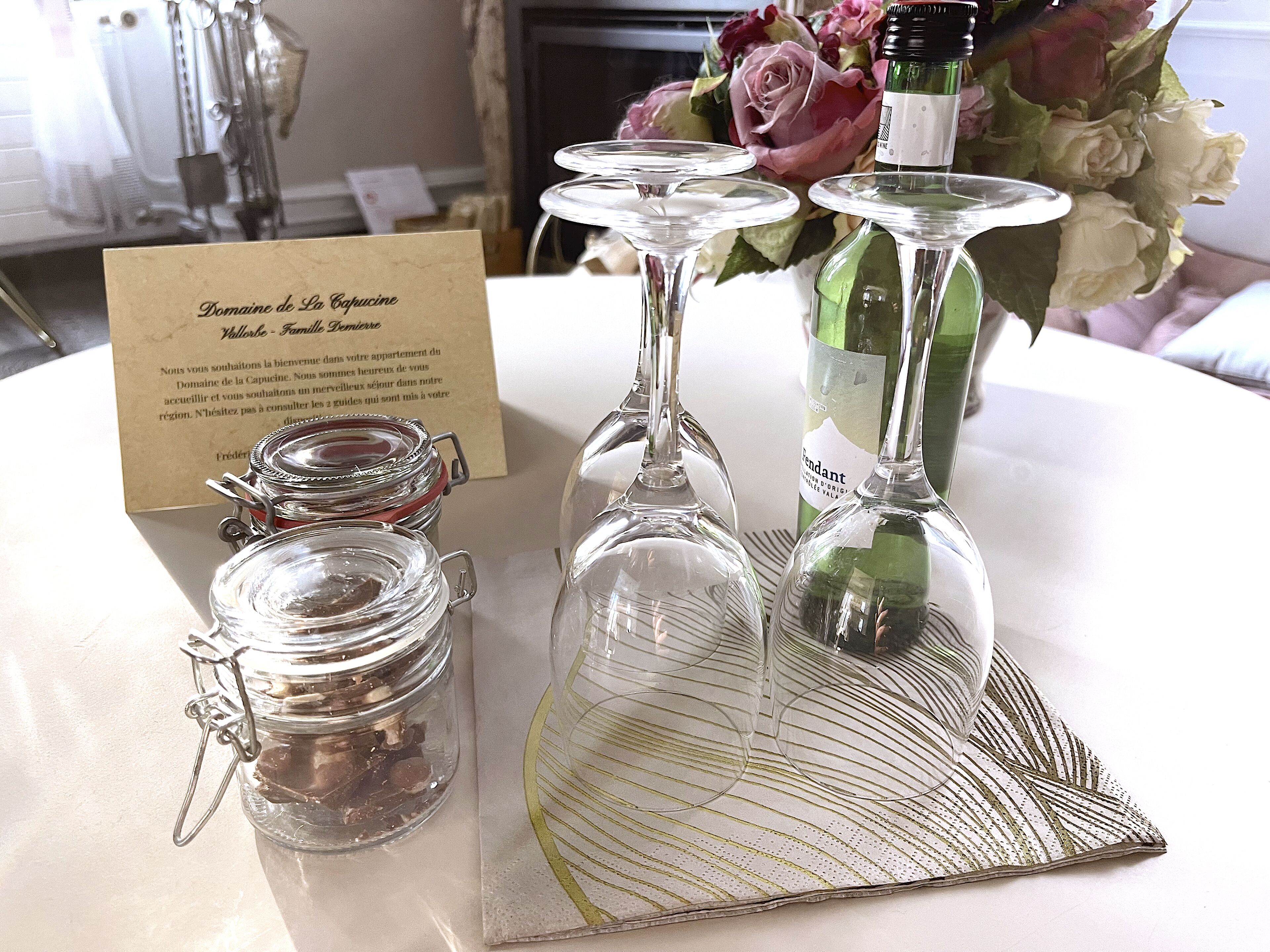 A table with a card, three wine glasses, and a bottle of wine.