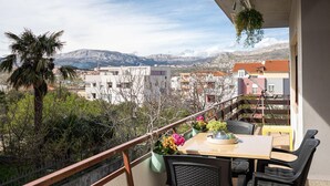 A balcony with a table and chairs, overlooking a cityscape with mountains in the background. - Pet friendly apartment in Podstrana with WiFi (Podstrana)