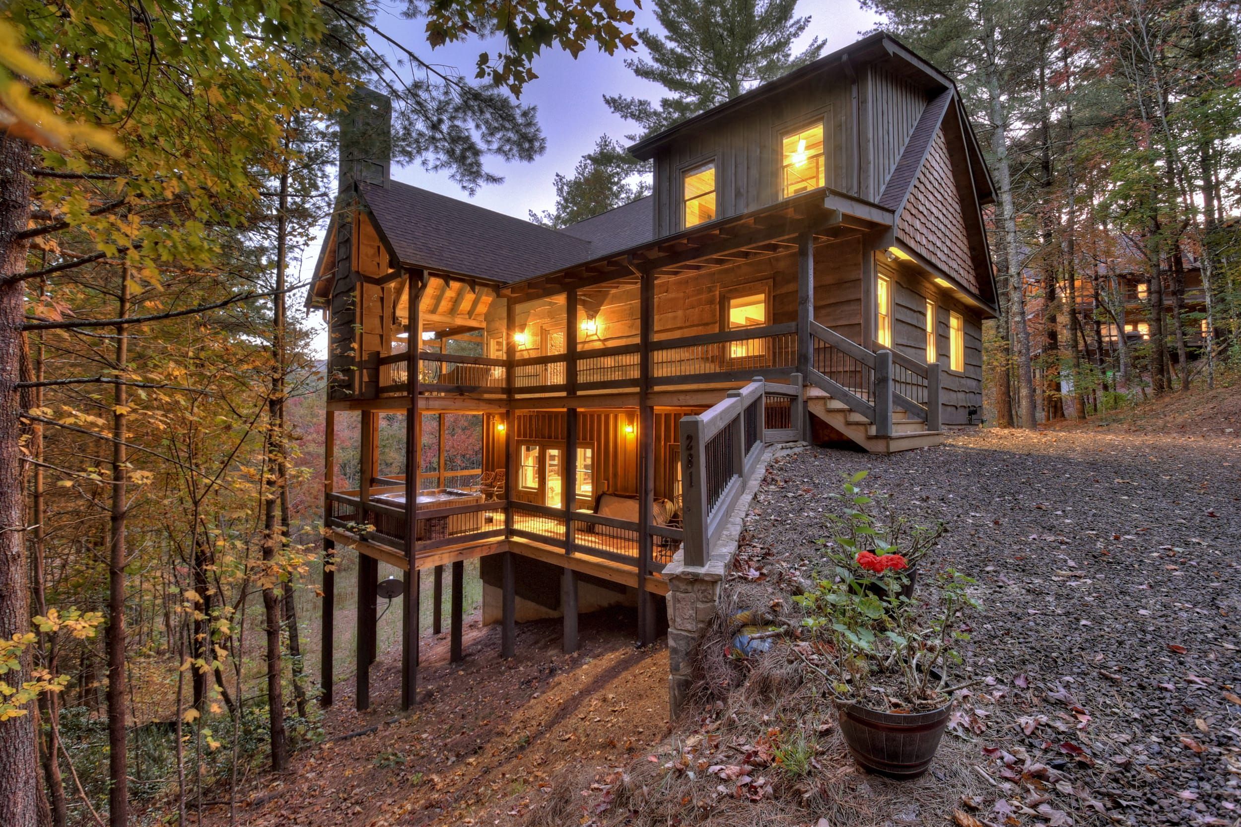 A multi-level wooden cabin with a balcony, surrounded by trees.