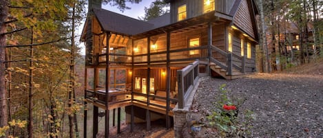 A multi-level wooden cabin with a balcony, surrounded by trees.