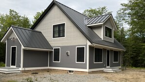 Ein zweigeschossiges Haus mit Satteldach, überdachter Garage und Schotterauffahrt.