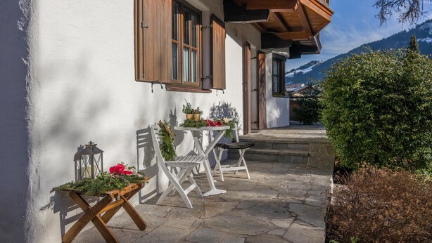 A traditional chalet with a stone-paved patio, wooden furniture, and a view of the mountains. - traditionelles Ferienh. Soell (Söll)