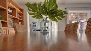 A wooden dining table with a clear glass vase containing a plant.
