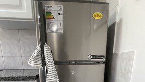 Un réfrigérateur en acier inoxydable dans une cuisine avec des armoires blanches et un pare-feu en carreaux.