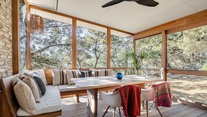 Eine Holzterrasse mit einer Couch, Stühlen und einem Tisch, mit Blick auf eine natürliche Landschaft.