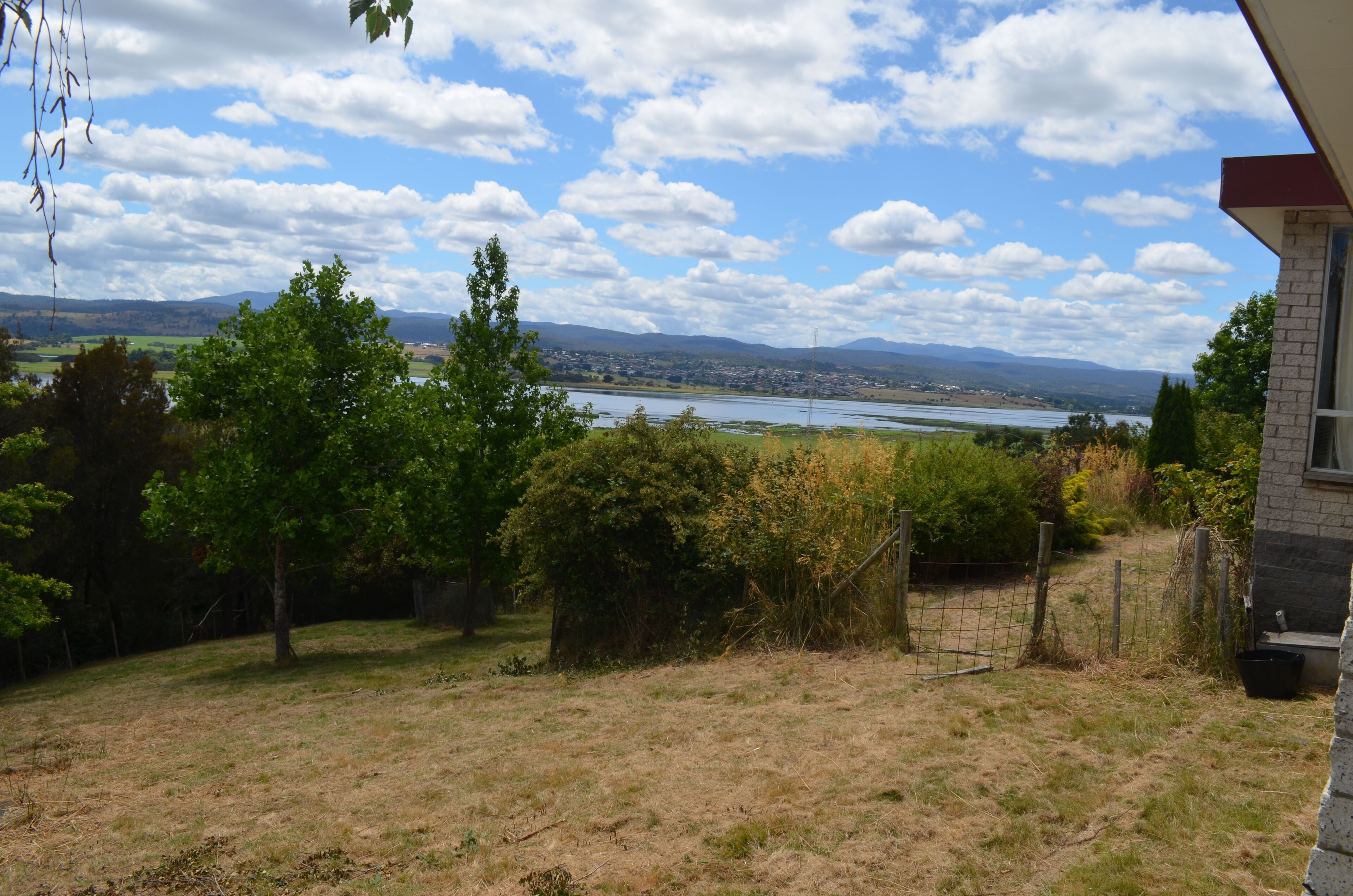 Une cour verdoyante offrant une vue sur une rivière et des montagnes au loin.