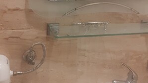 Une salle de bain avec un lavabo blanc, une étagère en verre, un miroir et une douche.