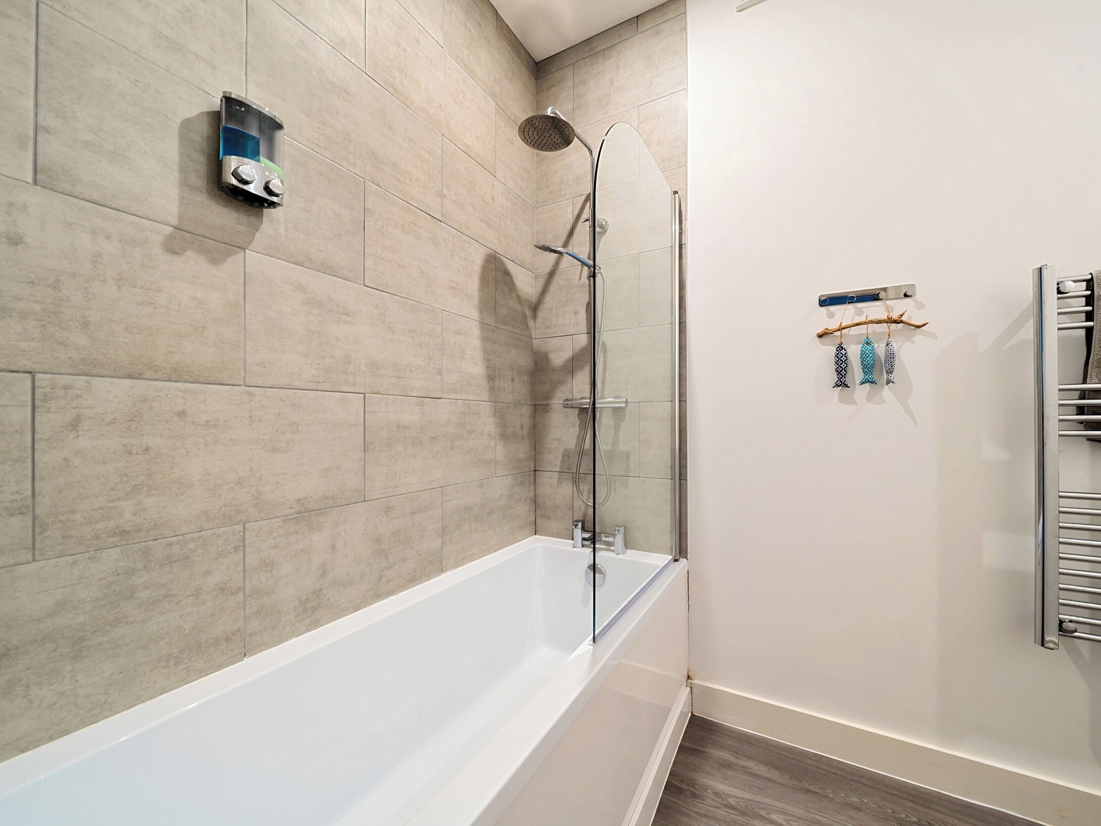 A modern bathroom with a bathtub, a shower, and a towel rack with decorative items.