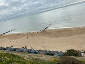 Una playa con un espigón de madera y cabañas de playa al frente.