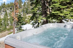 A hot tub surrounded by trees and a rocky landscape. - Stage Coach Run 5 Bedroom Home by RedAwning (Stateline)