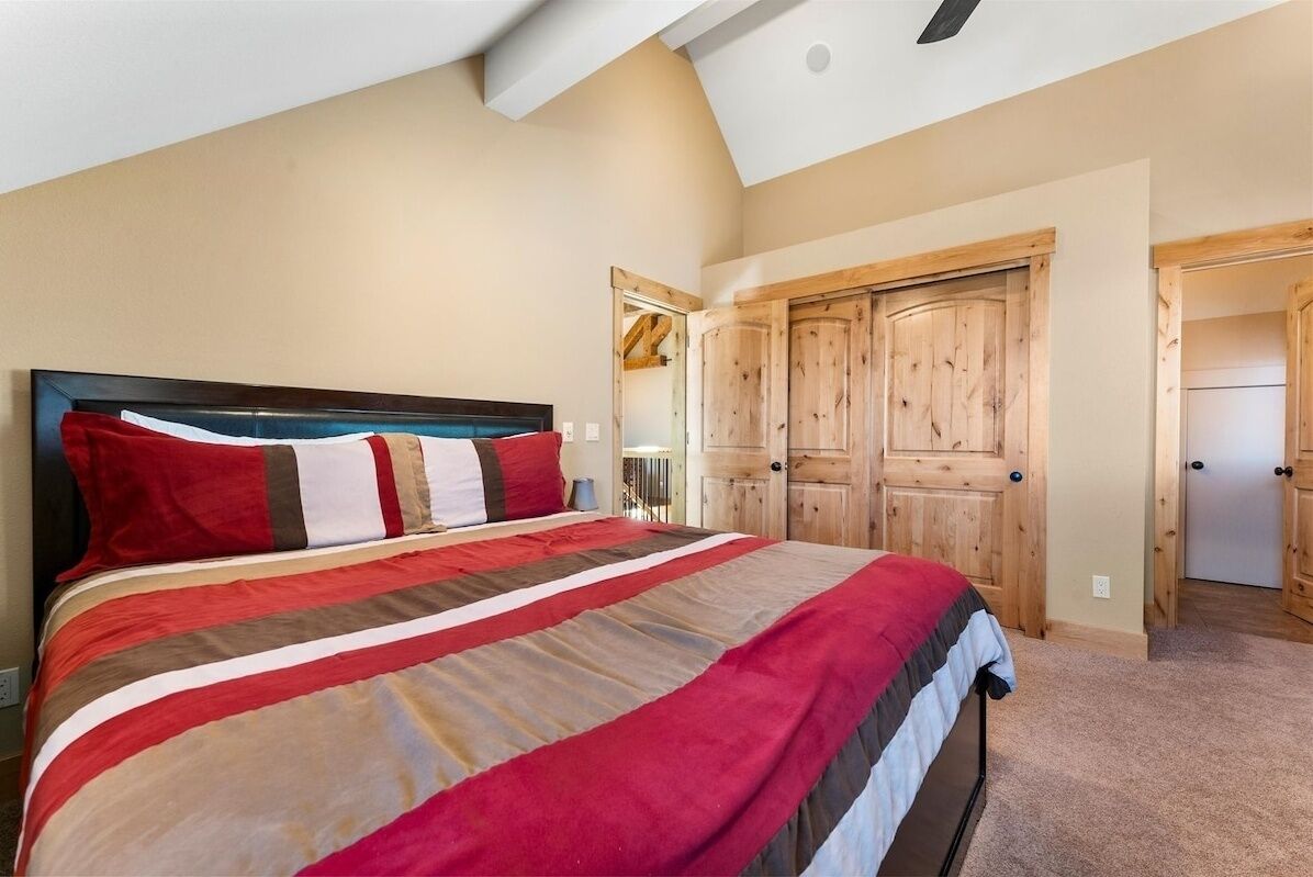 A bedroom with a large bed, wooden wardrobe, and a sloped ceiling.